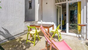 Une terrasse avec une table et deux chaises, une porte-fenêtre coulissante et une petite fenêtre.