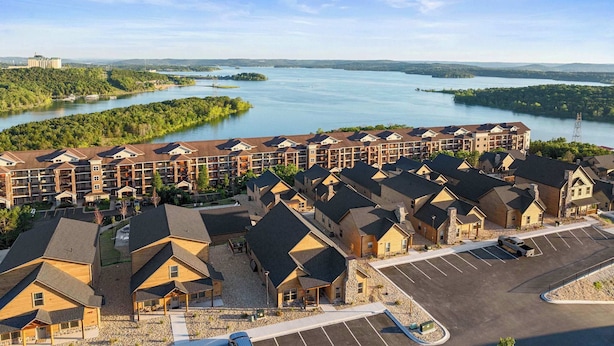 Ett hotellkomplex med flera byggnader, en parkeringsplats och utsikt över en sjö.
