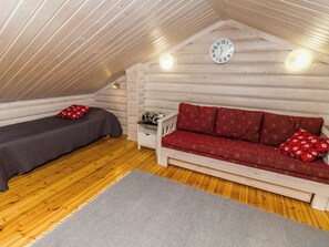 A cozy attic room with a wooden ceiling, a bed, a sofa, and a wall clock. - Rukanlyhty by Interhome (Kuusamo)