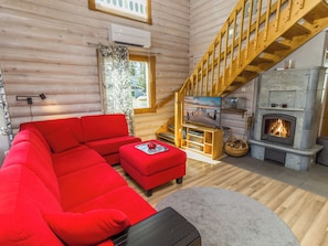 L’intérieur d’un chalet chaleureux, avec un canapé rouge, une cheminée et un escalier en bois.
