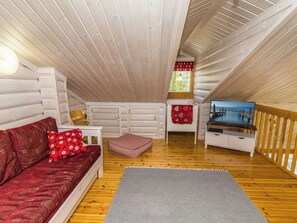 A cozy cabin interior with a wooden ceiling, a sofa, a small table, a television, and a window with a view. - Rukanlyhty by Interhome (Kuusamo)