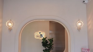 Un couloir intérieur avec un banc, une plante en pot et un luminaire fixé au mur.