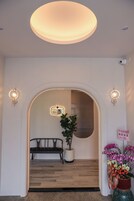 An interior hallway with a bench, a potted plant, and a wall-mounted light fixture.