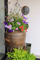 Una maceta de madera grande con una variedad de flores coloridas y follaje verde.