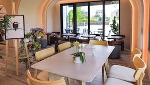 Un espace repas moderne avec une table blanche, des chaises en bois et des plantes en pot.