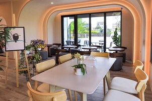Un comedor moderno con una mesa blanca, sillas de madera y plantas en macetas.
