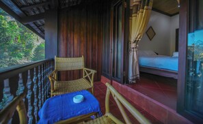 A balcony with wicker chairs, a small table with a cup, and a bed with a white bedspread. - Kosy Villa (Luang Prabang)