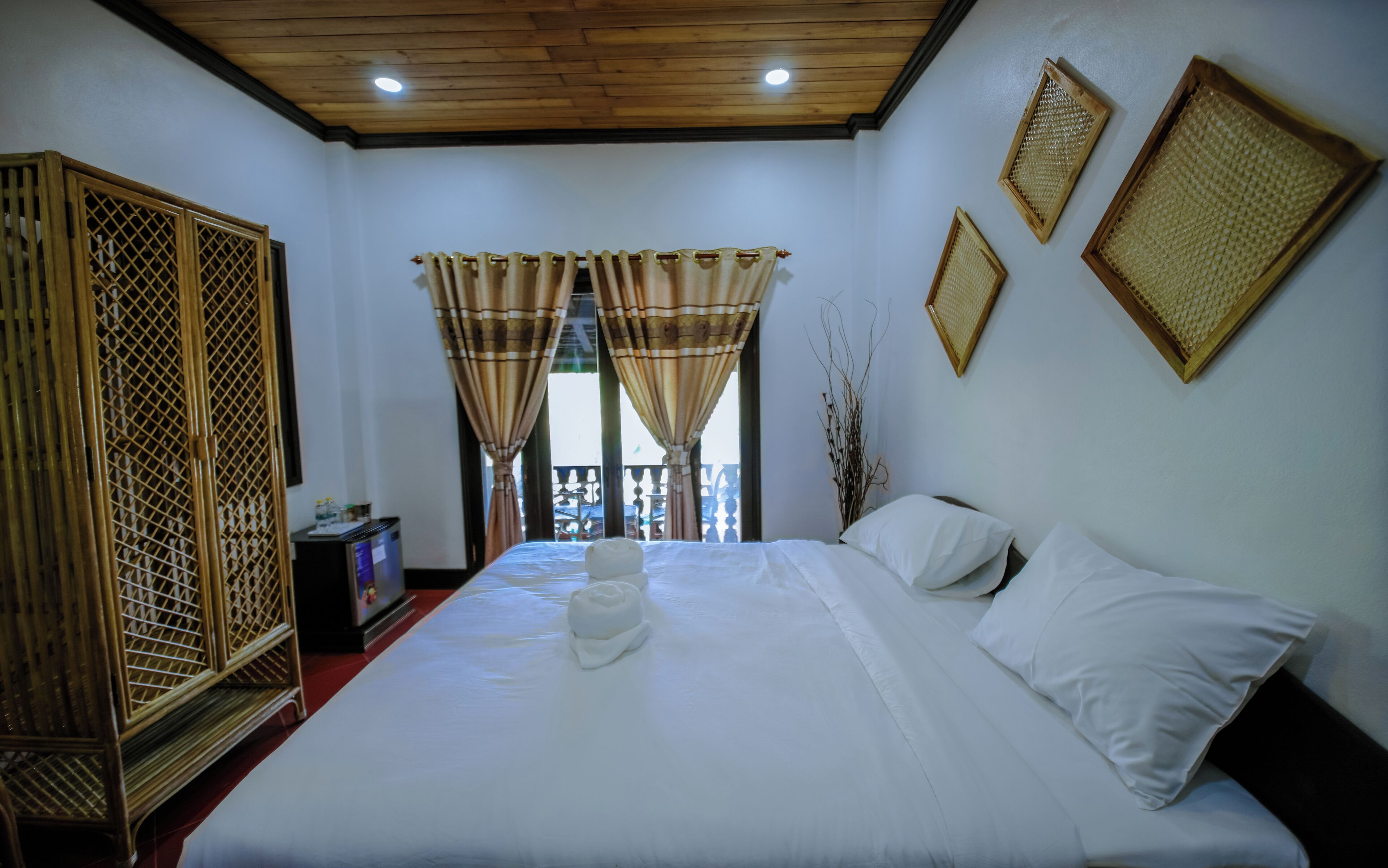 Habitación de hotel con una cama grande, cortinas, un armario de madera y una televisión.
