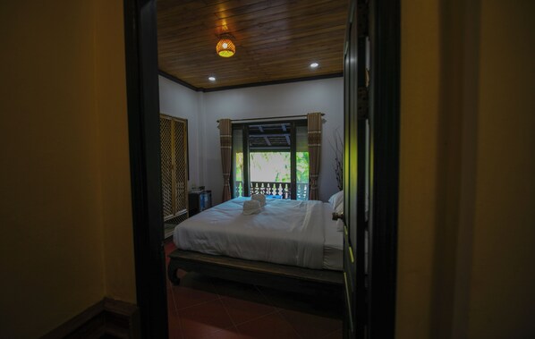 A room with a bed, a window with curtains, a ceiling light, and a view of greenery outside. - Kosy Villa (Luang Prabang)