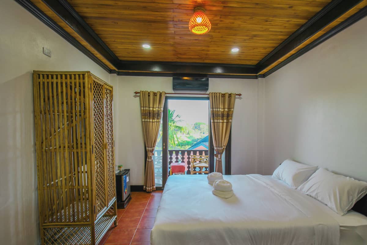 A hotel room with a bed, curtains, and a view of the outdoors.