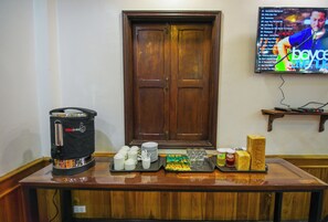 A buffet setup with a coffee maker, plates, cups, and condiments. - Kosy Villa (Luang Prabang)