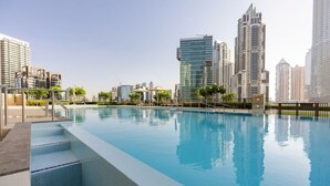 A swimming pool with steps leading into it, surrounded by high-rise buildings. - Luxury 1-Bedroom Apartment At Burj Crown. (Dubai)