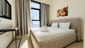 A hotel room with a bed, a desk, a TV, and a window with curtains. - Luxury 1-Bedroom Apartment At Burj Crown. (Dubai)