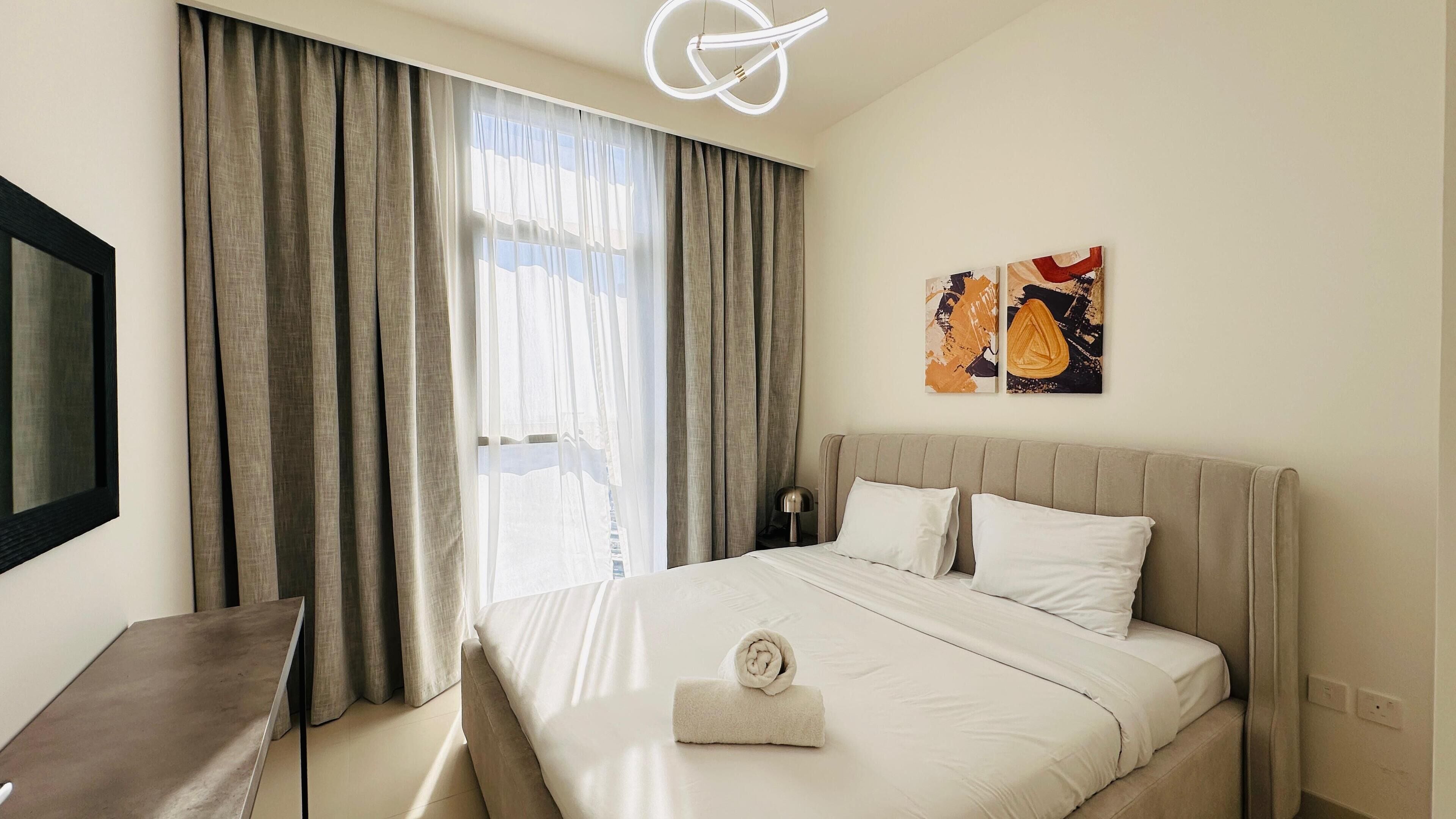 Une chambre d’hôtel avec un lit, une télévision, un bureau et une fenêtre avec des rideaux.