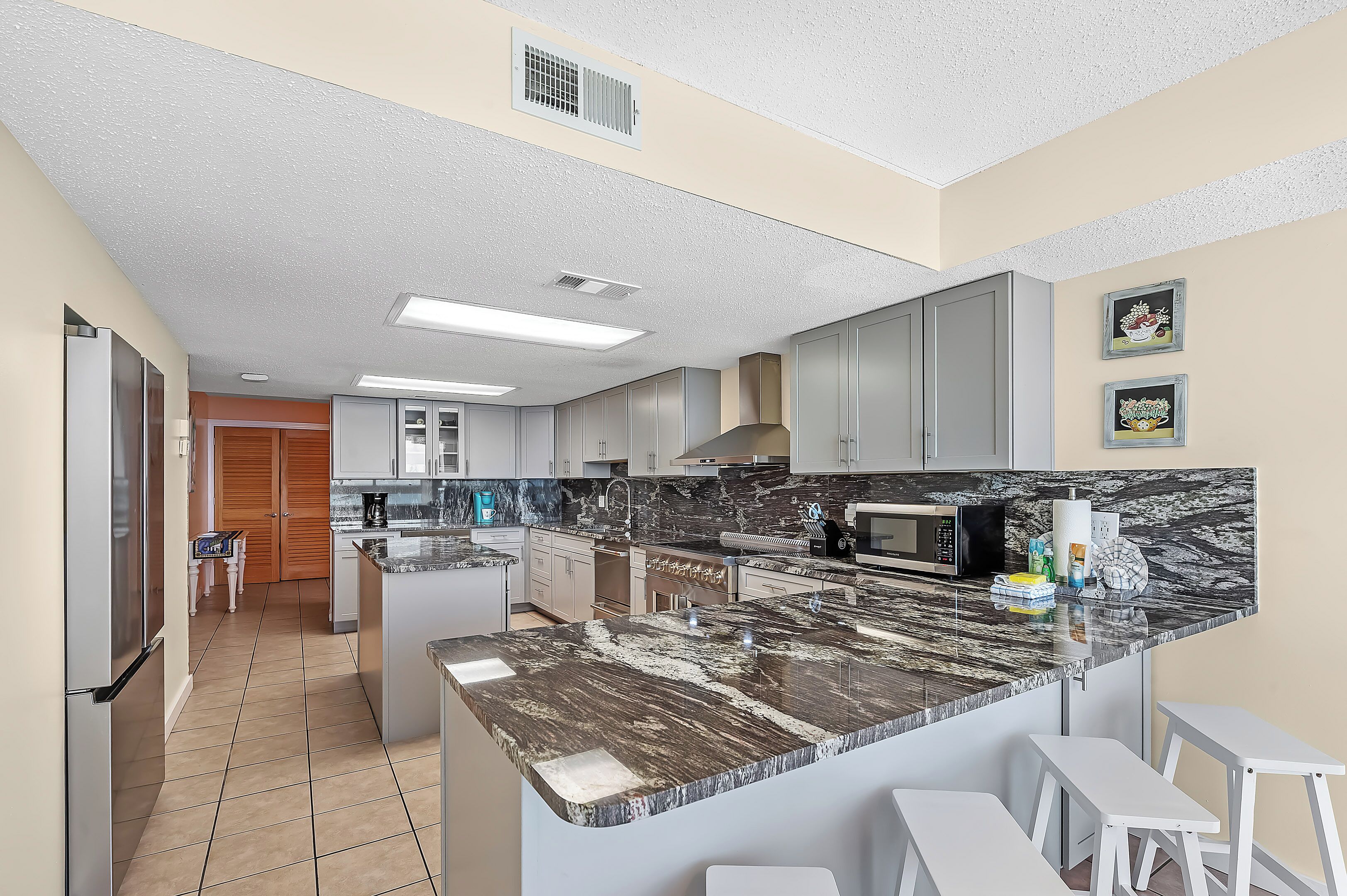 A modern kitchen with a marble countertop, white cabinets, and a built-in microwave.