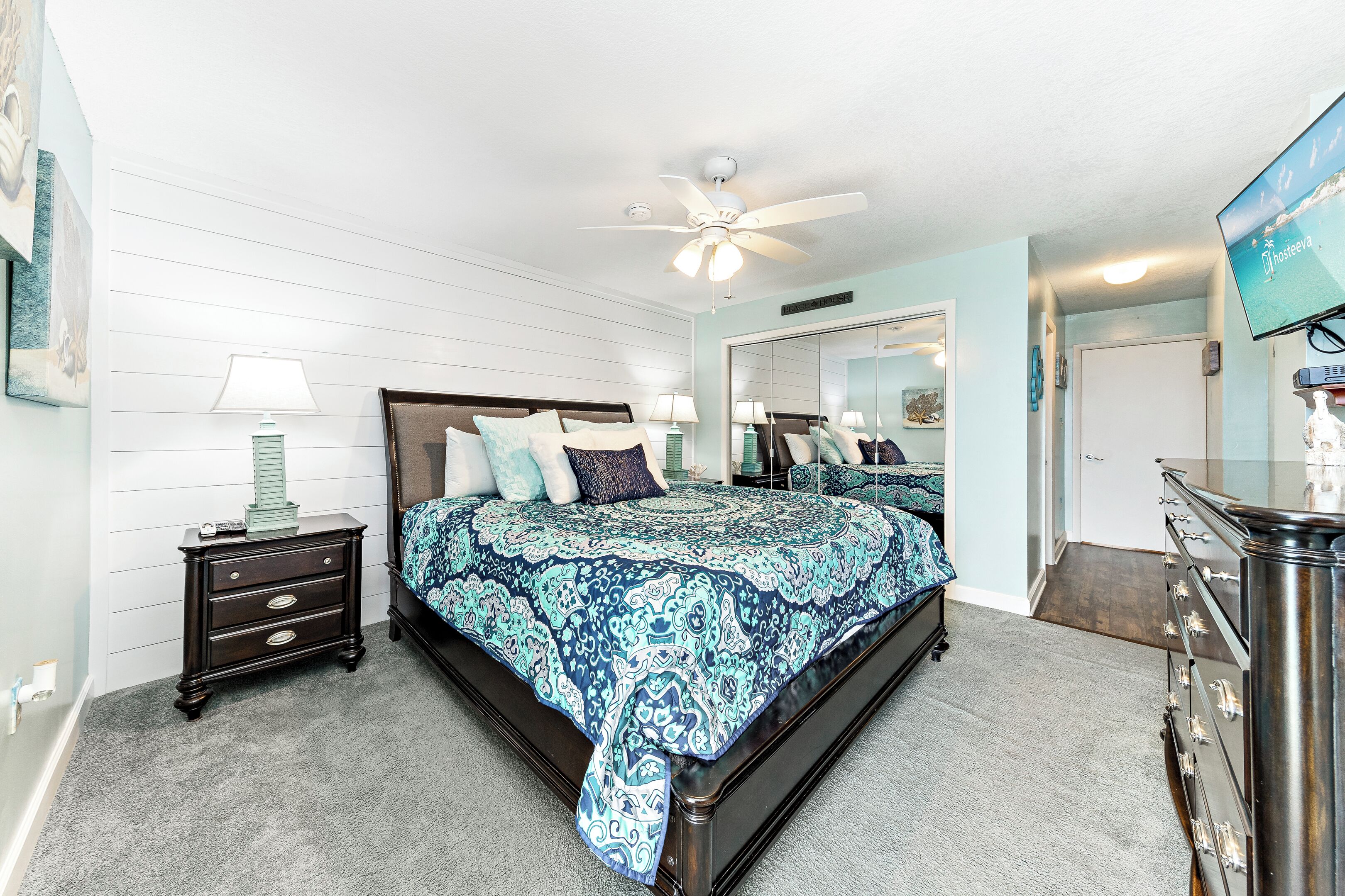 A bedroom with a bed, dresser, nightstand, and a ceiling fan.