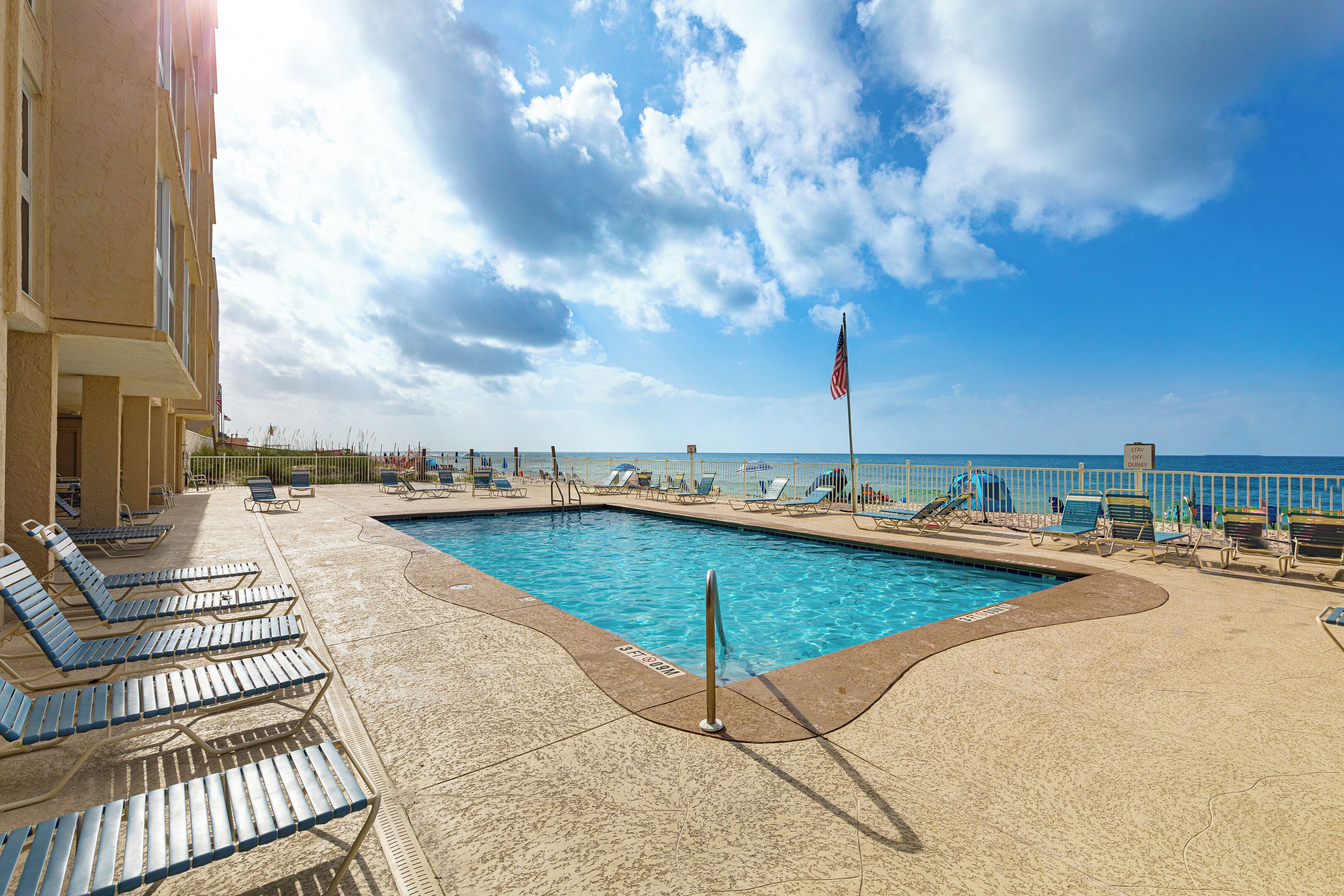 A swimming pool with lounge chairs and a view of the ocean.
