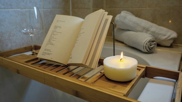 Un plateau en bois avec une bougie allumée, un menu ouvert et une serviette pliée.