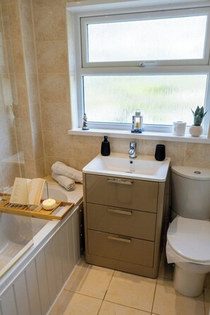 A bathroom with a bathtub, sink, toilet, and a window with a view.