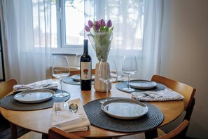 A dining table set with plates, cutlery, and a bottle of wine, with a vase of flowers in the center. - Garden House | Free Parking, Hospital & Reservoir (Birmingham)