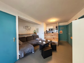 A compact living space with a kitchenette, a sofa, a dining table, and a small coffee table.