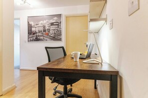 A wooden table with a laptop, a white mug, and a smartphone.