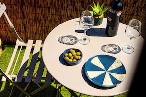 A round table with two wine glasses, a bottle, a bowl of olives, and a blue and white plate.
