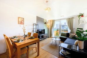 A modern living room with a dining area, a sofa set, a TV, and a large window with curtains.
