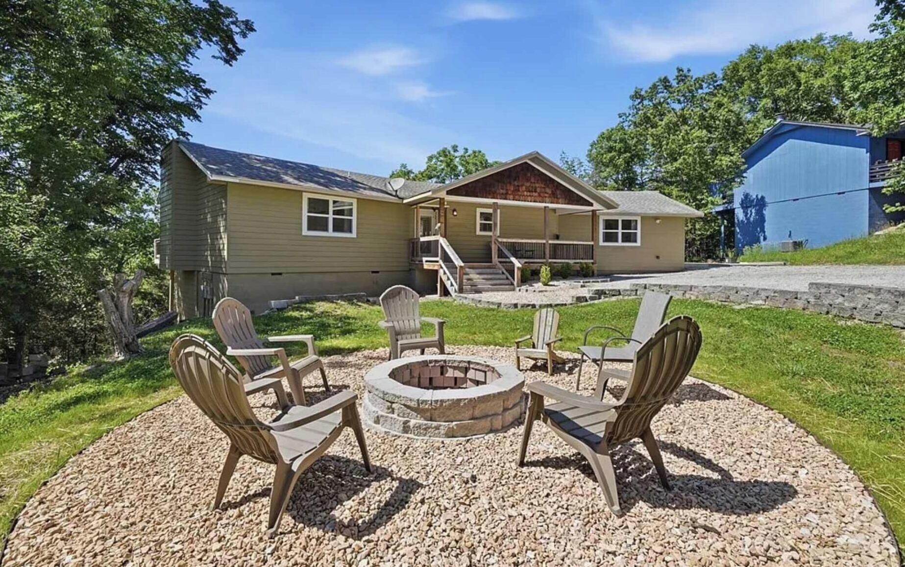 A house with a patio area featuring Adirondack chairs and a fire pit.
