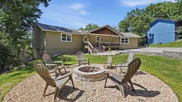A house with a patio area featuring Adirondack chairs and a fire pit.