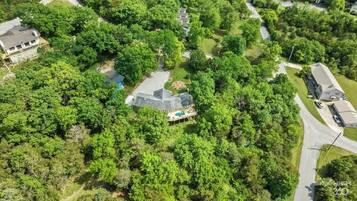 An aerial view of a residential area with a large house surrounded by dense trees.