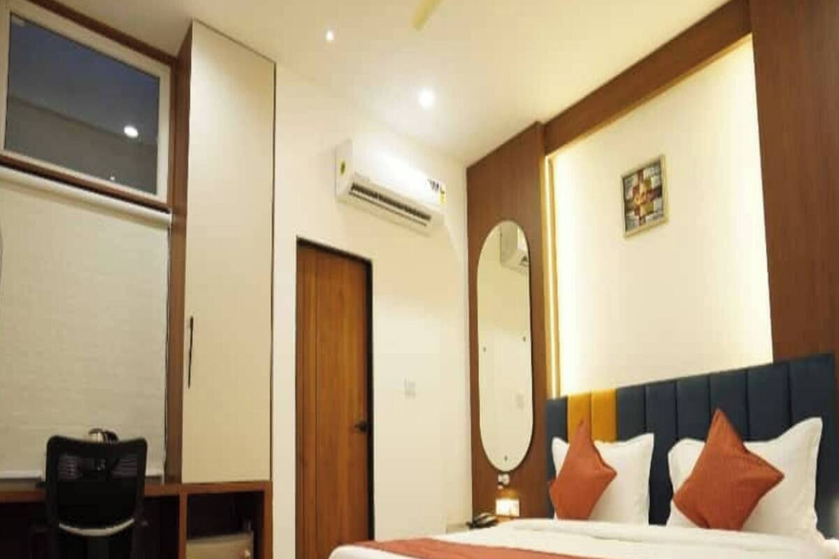 Une chambre d’hôtel avec un grand lit, un bureau avec une chaise, un appareil de climatisation et un miroir au mur.