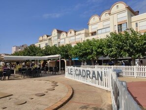 A hotel with a white facade, multiple balconies, and a covered outdoor seating area.