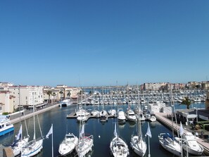 A marina with numerous boats docked, surrounded by buildings and a clear sky.