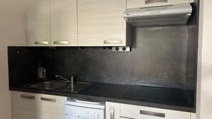 A compact kitchen with a dishwasher, a sink, and a stainless steel range hood. - Saint-Cyprien: Ground Floor T3, Terrace, Parking, 600m from Beach (Saint-Cyprien)