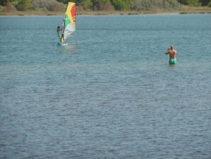 A person windsurfing on a calm body of water.