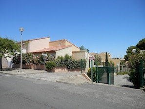 A residential building with a red-tiled roof, a gated entrance, and a clear blue sky.