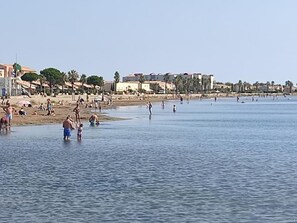 A beach with people swimming and walking along the shore.