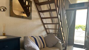 A cozy living room with a sofa, a wooden ladder, and a large mirror on the wall. - Charming 3-Room Villa with Mezzanine, Steps from Beach and Port in Saint-Cyprien (Saint-Cyprien)