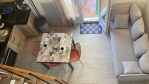 Eine moderne Küche mit Essplatz für vier Personen, einem roten Stuhl und einem grauen Sofa im Wohnbereich.