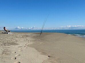 Une plage oĂč lâon voit des empreintes de pas menant Ă une chaise et Ă une canne Ă pĂȘche.