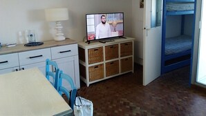 A room with a television on a white cabinet, a table with chairs, a bunk bed, and a small globe on the cabinet.