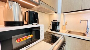 A compact kitchen with a microwave, coffee maker, and a kettle.