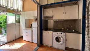 A compact kitchen with a washing machine, a coffee maker, and a sink. - Cosy T2 Mezzanine, Terrasse, Parking Privé, Proche Plage et Village, Idéal Famille, Animaux Ok (Gruissan)