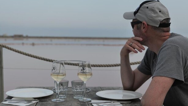 A wooden table with two wine glasses and plates, a rope barrier, and a view of the sea. - Cosy T2 Mezzanine, Terrasse, Parking Privé, Proche Plage et Village, Idéal Famille, Animaux Ok (Gruissan)