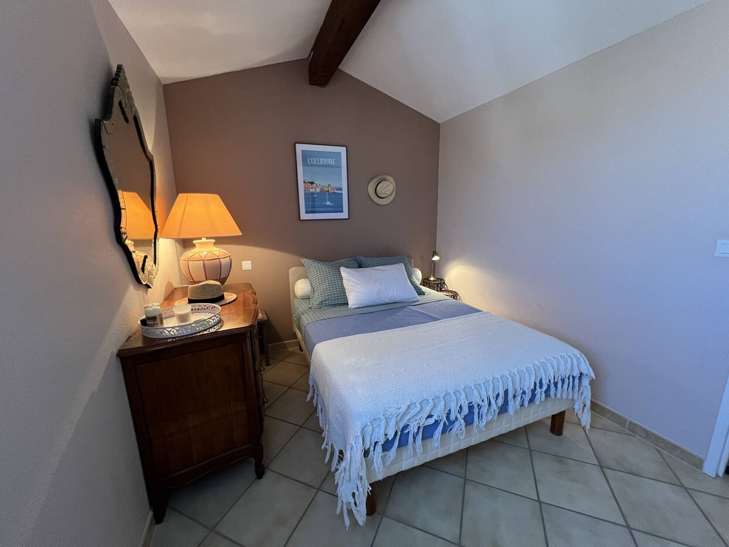Una camera da letto con un letto, comodini, una lampada, un quadro incorniciato e uno specchio.