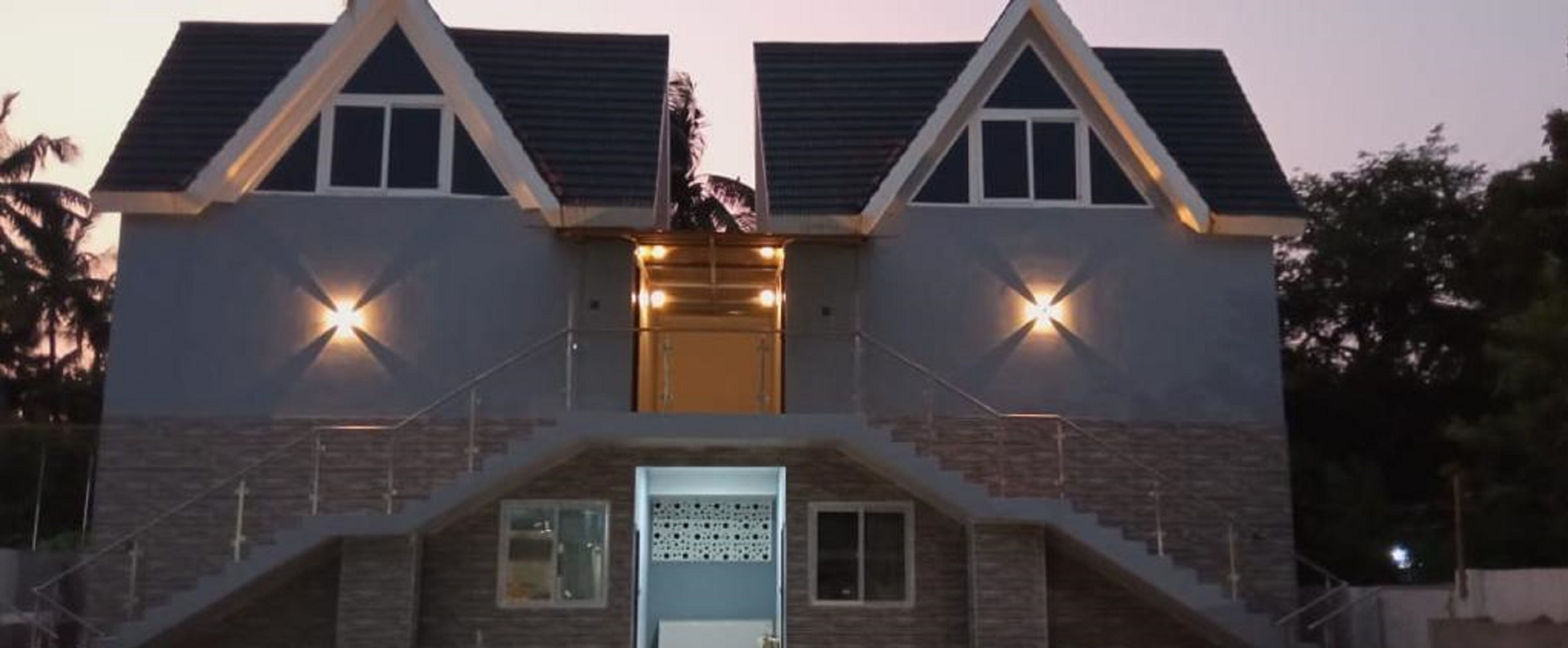 A two-story building with a central entrance, a staircase leading to the upper floor, and a balcony with railings.