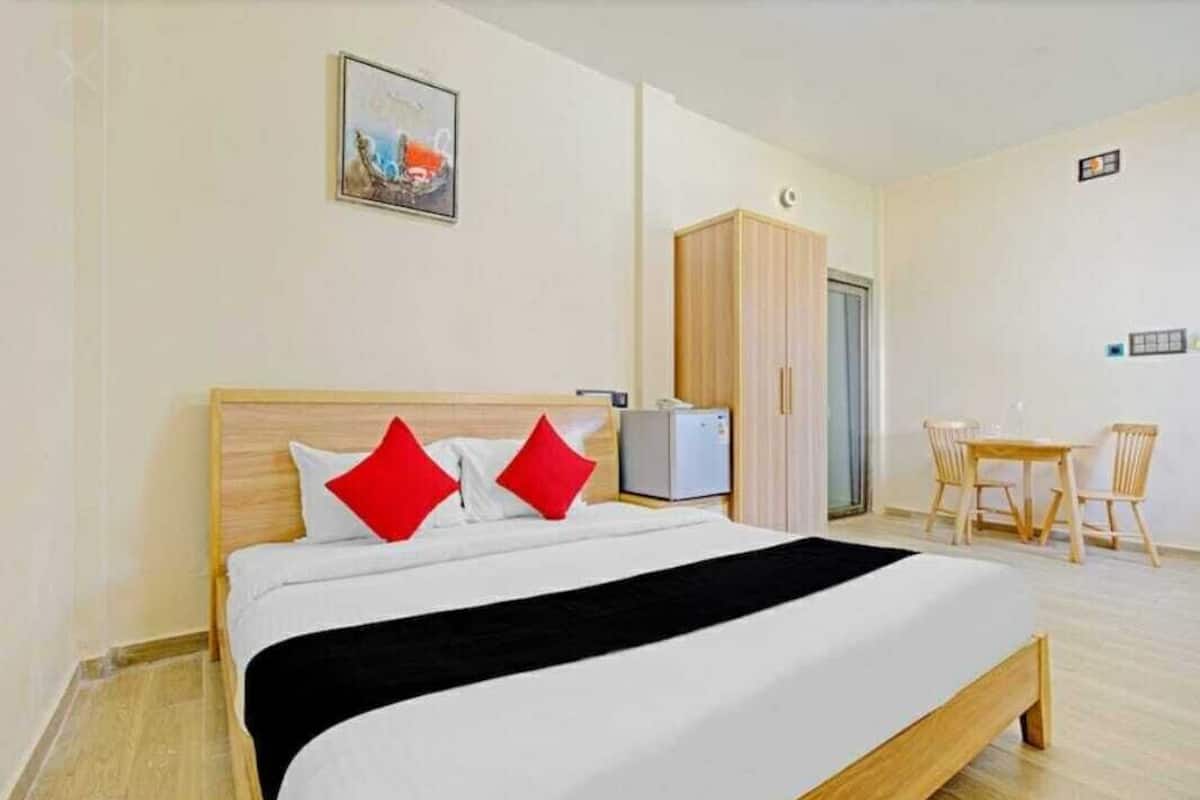 A hotel room with a bed, a desk, a wardrobe, and a chair.