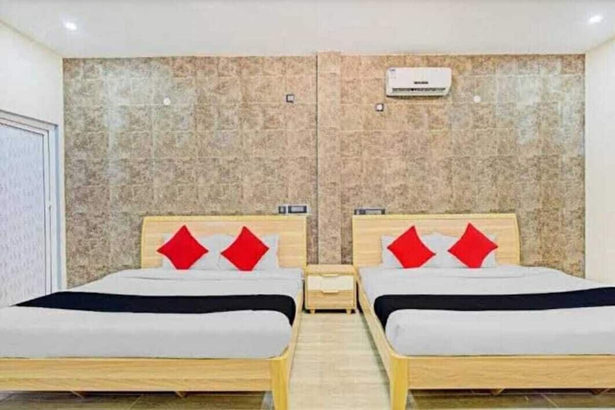 A hotel room with two beds, each with a wooden frame and red pillows.