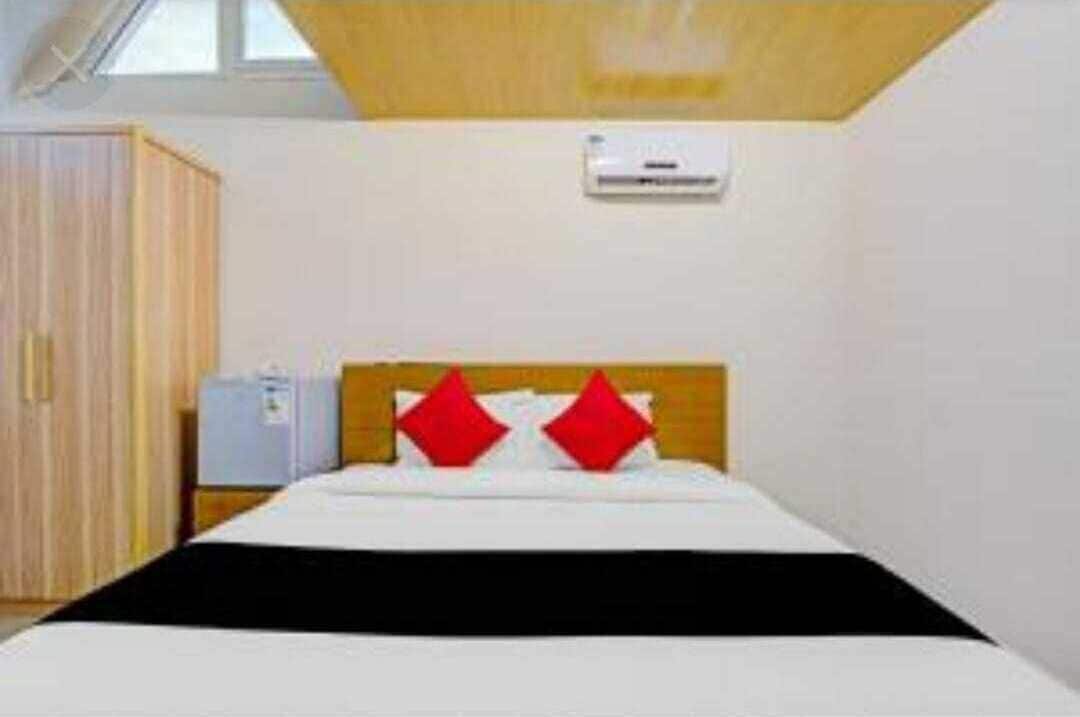 A hotel room with a bed, a wardrobe, and an air conditioning unit on the wall.
